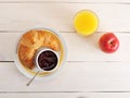 Croissant, jam, apple and orange juice on wooden background Royalty Free Stock Photo
