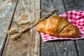Croissant with nuts on textile and spikelets, wooden background