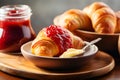 Croissant in a plate on a wooden board with butter and berry jam in a jar, breakfast food. Fresh oven-baked golden croissants on a