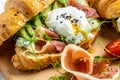 Croissant with prosciutto, poached egg, jamon, blue, cheese, avocado, microgin and cherry tomatoes. Mediterranean appetizer.