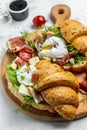 Croissant with prosciutto, poached egg, jamon, blue, cheese, avocado, microgin and cherry tomatoes. Mediterranean appetizer.