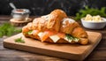 Croissant sandwich with cheese and salmon on wooden board, dark background, close up Royalty Free Stock Photo