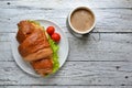 Croissant sandwich with chicken breast and lettuce. Croissant sandwich and coffee on a wooden table. Delicious Royalty Free Stock Photo