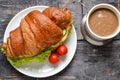 Croissant sandwich with chicken breast and lettuce. Croissant sandwich and coffee on a wooden table. Delicious Royalty Free Stock Photo