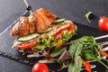 Croissant sandwich with fillet grilled chicken, fresh vegetables, cheese and greens on black shale board over black background Royalty Free Stock Photo