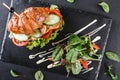 Croissant sandwich with fillet grilled chicken, fresh vegetables, cheese and greens on black shale board over black background Royalty Free Stock Photo