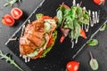 Croissant sandwich with fillet grilled chicken, fresh vegetables, cheese and greens on black shale board over stone background Royalty Free Stock Photo
