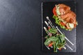 Croissant sandwich with fillet grilled chicken, fresh vegetables, cheese and greens on black shale board over stone background Royalty Free Stock Photo