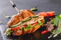 Croissant sandwich with fillet grilled chicken, fresh vegetables, cheese and greens on black shale board over black stone Royalty Free Stock Photo