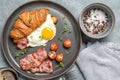 Croissant sandwich with fried egg, bacon, tomato, microgreens, coffee. Delicious appetizing breakfast. Gray grunge Royalty Free Stock Photo