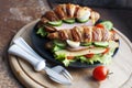 Croissant sandwich with ham, cheese, fresh salad and tomatoes on black plate Royalty Free Stock Photo