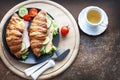 Croissant sandwich with ham, cheese, fresh salad, tomatoes and tea Royalty Free Stock Photo
