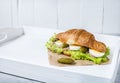 Croissant sandwich with tuna, hard boiled egg, salad and cucumber on white tray. Breakfast concept Royalty Free Stock Photo
