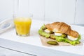 Croissant sandwich with tuna, hard boiled egg, salad and cucumber on white tray. Glass of orange juice. Breakfast Royalty Free Stock Photo