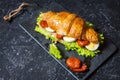 Croissant sandwich with tuna, hard boiled egg, salad and sun-dried tomatoes on stone table Royalty Free Stock Photo