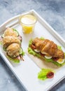 Croissant sandwich with tuna, hard boiled egg, salad and sun-dried tomatoes on white tray. Glass of orange juice. Royalty Free Stock Photo