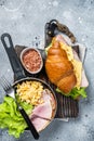 Croissant sandwich with turkey ham, scrambled eggs, cheese and lettuce salad. Gray background. Top view Royalty Free Stock Photo