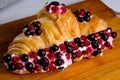 Croissant sandwiche with berries on a wooden background