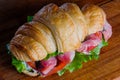 Croissant sandwiche with salmon red fish on a wooden background