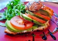 Croissant sandwiches with fresh tomato slices, avocado and arugula with balsamic sauce
