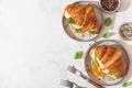 Croissant sandwiches with poached egg, avocado, soft cheese, mozzarella and tomato in a plate with forks Royalty Free Stock Photo