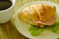 croissant stuffed pork bologna and green oak with black coffee
