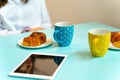 Croissants and coffee mugs for two on an office table with a tablet - Breakfast Royalty Free Stock Photo