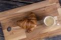 Croissants with a cup of coffee on a wooden board.