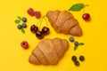 Croissants, flowers and berries on yellow background Royalty Free Stock Photo
