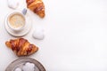 Croissants, glazed cookies and a cup of coffee on a white wooden table. Morning still life. Top view with space for text.