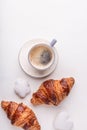Croissants, glazed cookies and a cup of coffee on a white wooden table. Morning still life. Top view with space for text.