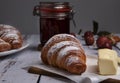 Croissants strawberry jam and butter lie on a wooden table