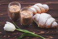 Croissants and two glasses of frothy coffee on a dark brown wooden table. French breakfast concept, break. Drinks and sweets, puff Royalty Free Stock Photo