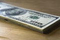 Crolled stack of 100 new dollar bills on wooden background Royalty Free Stock Photo