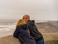 Couple leaning against the wall looking out to sea in the seaside town of Cromer