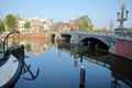 Crooked and colorful heritage buildings and houseboats, overlooking Amstel river with perfect reflections, with Blauwbrug bridge