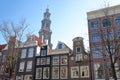 Crooked and colorful heritage buildings, located along Bloemgracht Canal, with Westerkerk church clocktower in the background