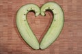 Crooked cucumber, cut in half and placed in a heart shape. Wood background