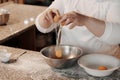 Crop female cook cracking egg into bowl