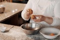 Crop female cook cracking egg into bowl