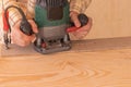 Crop anonymous male carpenter using electric milling machine while cutting wood plank in home workshop Royalty Free Stock Photo