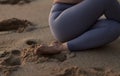 Crop anonymous woman performing Shoelace yoga pose on sandy seashore