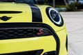 Crop of bright yellow and black front bumper of glossy automobile with led headlight and brand symbol letter S parked