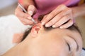 Crop chiropractor massaging ear of woman during auriculotherapy in beauty salon