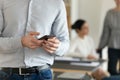 Crop of male employee using modern cellphone in office