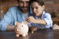 Crop close up family putting coin into pink piggy bank Royalty Free Stock Photo