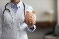 Crop close up female doctor physician holding pink piggy bank Royalty Free Stock Photo