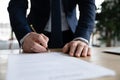 Close up of businessman sign paper closing deal in office