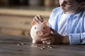 Crop close up 8s boy putting coin into piggy bank Royalty Free Stock Photo