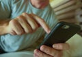 Crop face portrait with close up hands holding mobile phone of young man at home bedroom using internet social media app on smartp Royalty Free Stock Photo